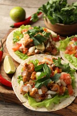 Delicious tacos with vegetables, meat and lime on table, closeup