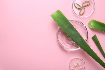 Flat lay composition with aloe vera leaves and cosmetic gel on pink background. Space for text