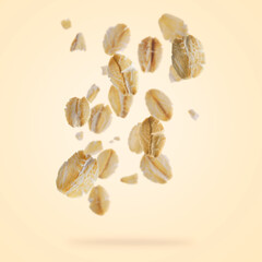 Rolled oat flakes falling on beige background