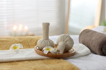 Fototapeta na wymiar Herbal bags, flowers and towels on massage table in spa