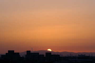 生駒山系から朝日が登る時。神戸市内から芦屋のビルと山並みをシルエットで撮影。
