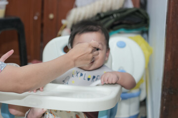 Asian mother feeding her 6 month old son. 