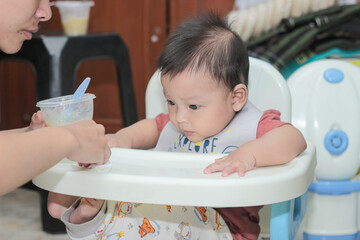 Asian mother feeding her 6 month old son. 