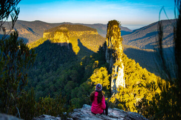 hiker girl enjoys the sunset over unique australian mountains in main range national park, queensland; famous steamers trailhead near mount superbus