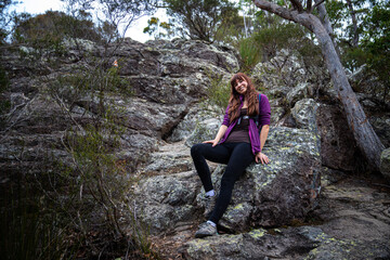 brave fit girl climbing to the top of mount maroon; rock scrambling in mount barney national park...