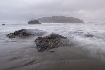 A rocky shoreline with a foggy, misty atmosphere