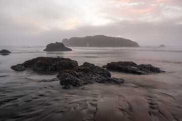 A rocky shoreline with a foggy sky in the background