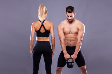 Sports couple with dumbbells on a dark background - 749681177