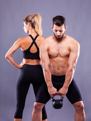 Sports couple with dumbbells on a dark background - 749681188