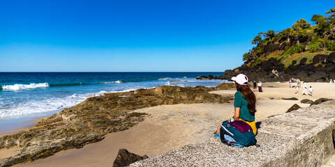 girl looking for whales from the cliffs of point danger above duranbah beach in coolangatta near gold coast, queensland, australia; relaxing coastal walk in a scenic area - obrazy, fototapety, plakaty