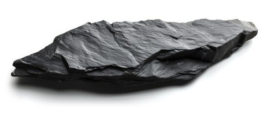 A black slate stone stands out boldly against a plain white background. The contrast between dark and light creates a striking visual effect. - obrazy, fototapety, plakaty