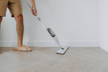 Close up of man leg, hand holding and using mop for cleaning floor in living room apartment, Man do household chores, housework concept. lifestyle routine concept.