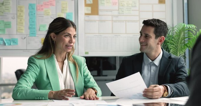Pretty Hispanic businesslady, team leader lead formal meeting with clients sit at desk with papers share thoughts, vision, opinion, communicate with investors, planning cooperation engaged in briefing
