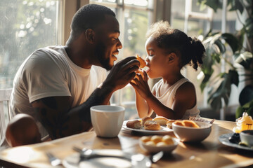 Fototapeta na wymiar father feeds his daughter during breakfast at dining table