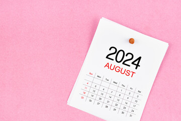 August 2024 calendar page and wooden push pin on pink background.