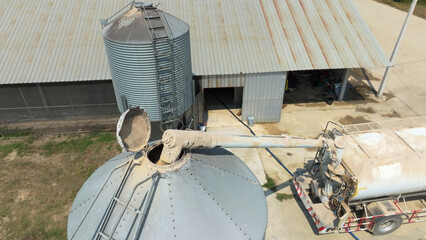 Feed truck delivering feed to the storage bins of chicken houses.. © toa555