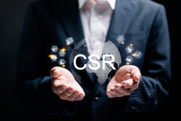CSR, Community Social Responsibility concept. Businessman holding globe with CSR icons on virtual screen. Corporate social responsibility and giving back to the community.