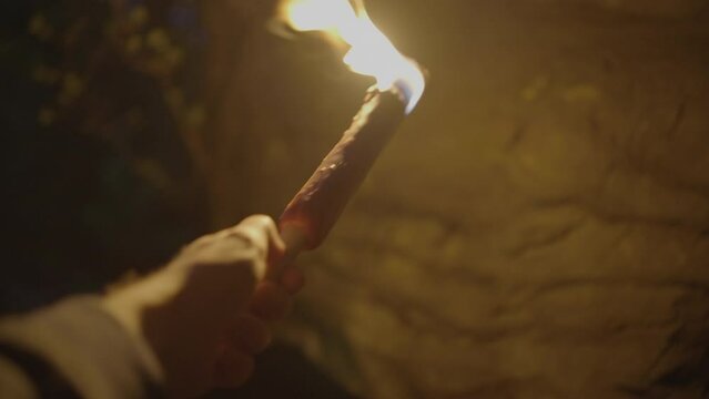 Person Holding Flaming Burning Torch Light In Stone Cave Forest At Night