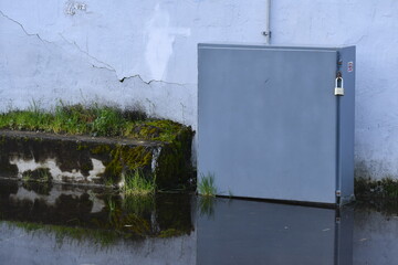 Electrical box in pool of water. Exterior of building. Padlocked.