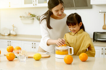 Making in the kitchen Asian mother making juice for daughter to drink