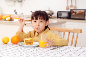 Made in kitchen Asian daughter drinks juice and eats bread