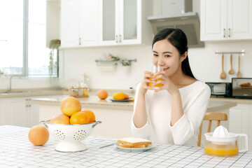 Asian girl drinking juice in kitchen