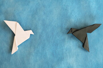 White dove and black rave paper origami in blue background. Good and evil, face fear and opposite...