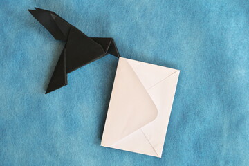 Black raven paper origami carrying white letter envelope. Email, message, courier and letter...