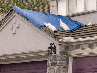 Blue tarp with sandbags on a houde roof during a storm © F Armstrong Photo