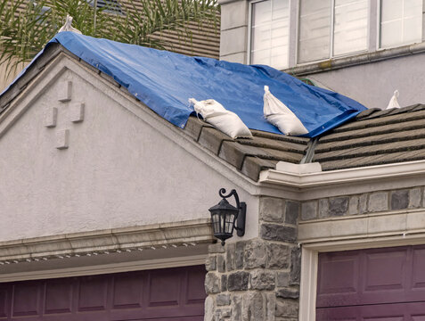 Blue tarp with sandbags on a houde roof during a storm