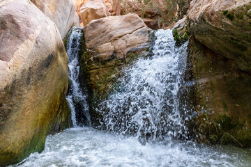 Low waterfall in path of shallow stream in the gorge Wadi Al Ghuwayr or An Nakhil and the wadi Al...