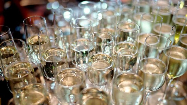 A collection of champagne glasses are neatly stacked on a table, ready for guests to enjoy a celebratory drink at the event. The beautiful glassware adds elegance to the barware display