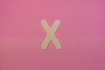 Obraz premium Letter X in wood on a pink background