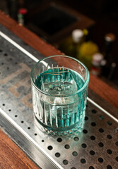 The bartender presents an emerald cocktail with the color of the sea wave