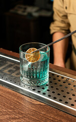 The bartender presents an emerald cocktail with the color of the sea wave