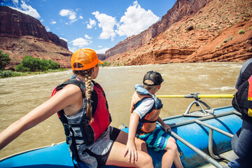 Active young family enjoying a fun whitewater rafting trip down the Colorado River. Fun in the sun as they head down the river. - obrazy, fototapety, plakaty