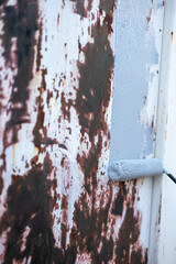 Anti-rust primer paint roller, on the rusty metal panel