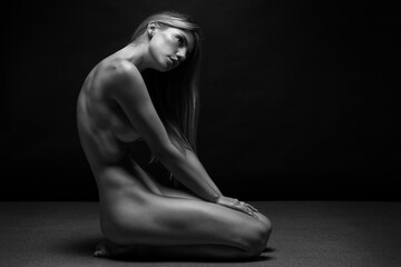 Abstract fine-art portrait. Black and white photo of nude beautiful woman. Female body on black background.	
