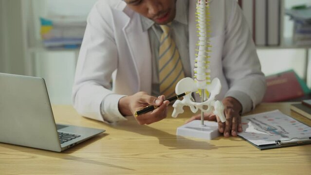 Doctor explaining bone problems behind the concept of health care and healthy living Male orthopedic surgeon or traumatologist tells patient about her diagnosis in the form of a spinal disc.