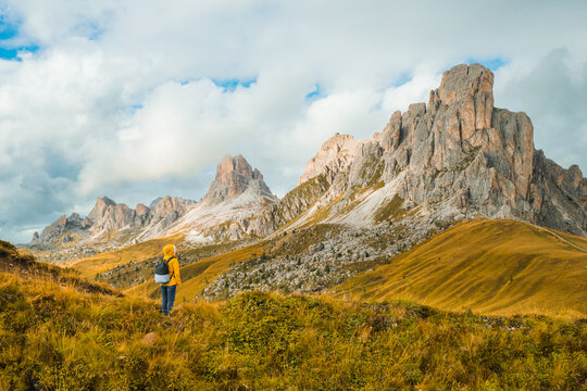 Tourist in yellow jacket and backpack enjoying the famous Giau Pass and Dolomites Alps