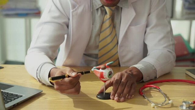 African American male doctor suspects eye disease using eye care concept model. Doctor uses technology to check your eyesight. Make an appointment at the eye clinic