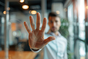 Businessman gesturing stop with his hand against a blurred office background