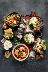 Fototapeta na wymiar Traditional Asian food table. Spring roll, rice, shrimp, sushi, vegetables, meat on dark background