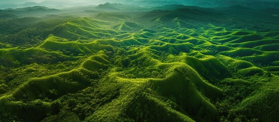 This aerial view showcases a sprawling green mountain range, with lush vegetation covering the rugged terrain. The peaks and valleys of the mountains create a captivating landscape that appears