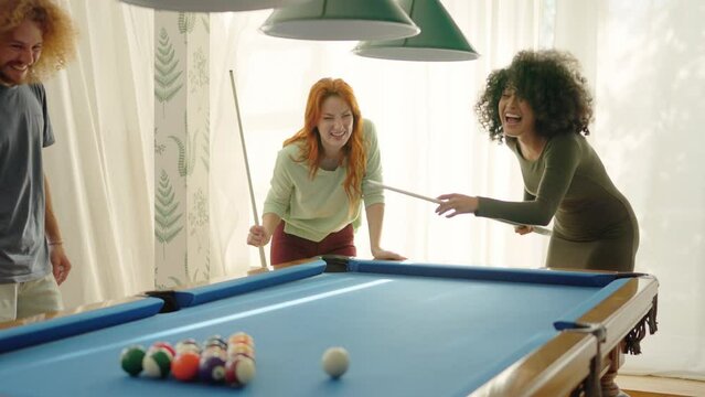 Friends laughing when woman playing awful at pool