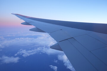 Fototapeta na wymiar Sunrise and Wing of Aircraft from Window - 飛行機の翼と朝日