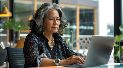 Middle aged hispanic woman at work with laptop