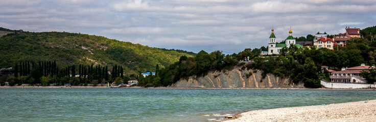 View of the church on the mountain. View of Lake Abrau-Durso from the shore. In the village of Abrau-Durso, on the mountain stands the Church of Blessed Xenia of Petersburg.