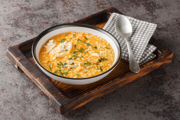 Homemade puree soup with pastina, chicken, vegetables and cheese close-up in a bowl on a wooden board. Horizontal
