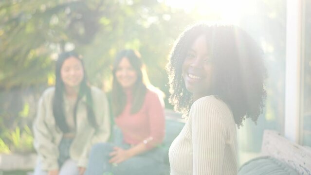 African woman smiling while chatting on the garden with friends
